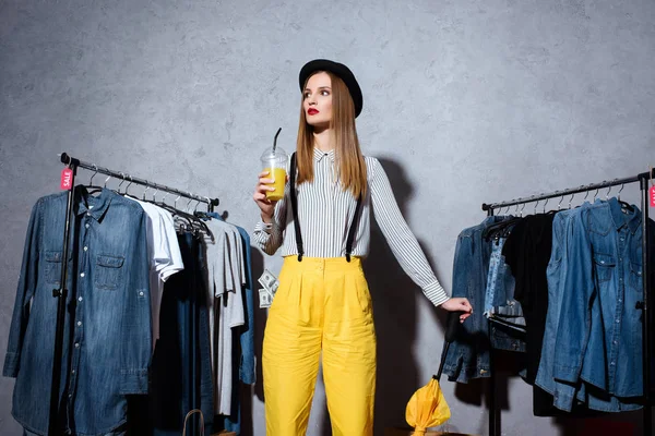 Chica en boutique con ropa alrededor - foto de stock