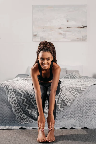 Mujer en ropa deportiva sentada en la cama - foto de stock