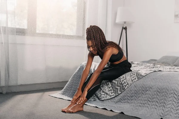 Frau in Sportbekleidung sitzt auf Bett — Stockfoto