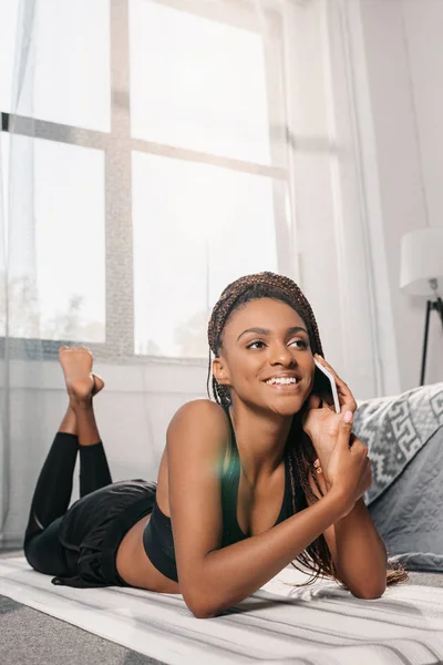 Женщина разговаривает по телефону на коврике для йоги — стоковое фото