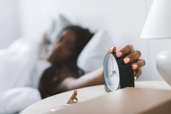 Woman turning alarm clock off — Stock Photo