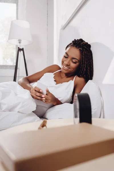 Frau benutzt Smartphone im Bett — Stockfoto