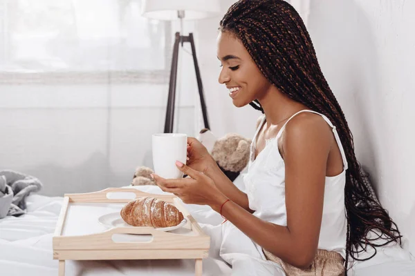 Mujer afroamericana desayunando en la cama - foto de stock