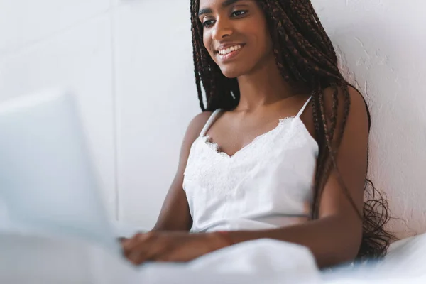 Woman using laptop in bed — Stock Photo