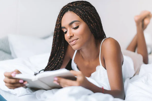 Mujer leyendo libro en la cama - foto de stock