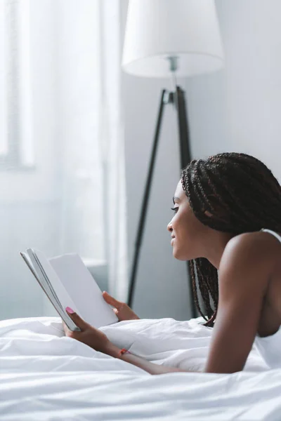 Donna che legge libro a letto — Foto stock