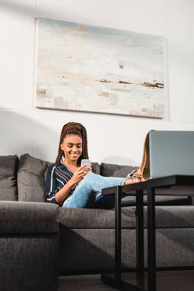 Femme utilisant un smartphone sur le canapé — Photo de stock