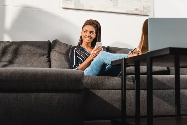 Mujer usando smartphone en sofá - foto de stock