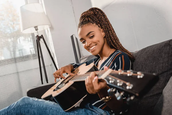 Frau spielt Gitarre auf Couch — Stockfoto