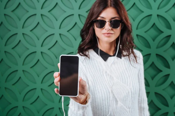 Woman in winter sweater showing smartphone — Stock Photo