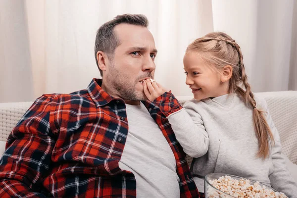 Отец и дочь едят попкорн — стоковое фото