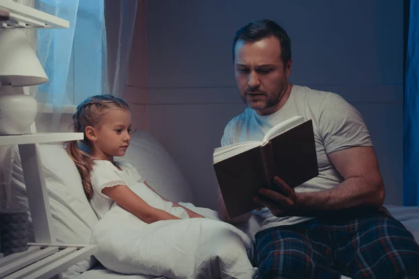 Family reading book at bedtime — Stock Photo