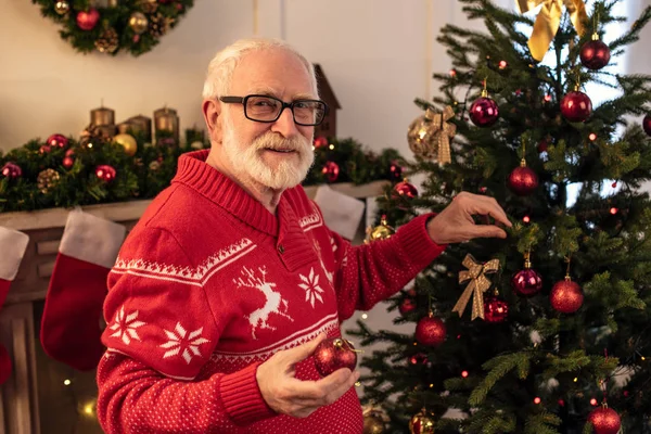 Senior man decorating christmas tree — Stock Photo