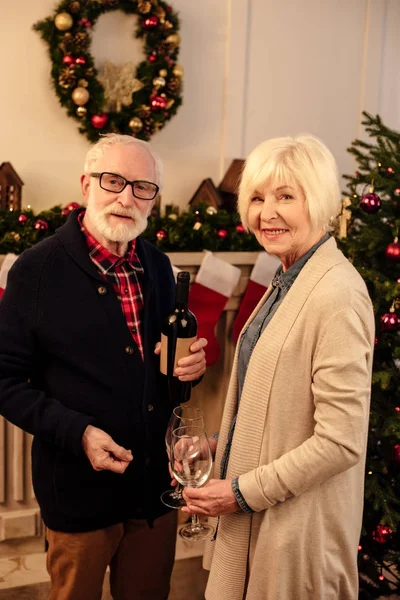 Pareja de ancianos con vino en Navidad - foto de stock