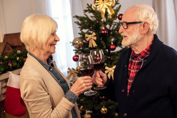 Pareja mayor tintineo con copas de vino - foto de stock