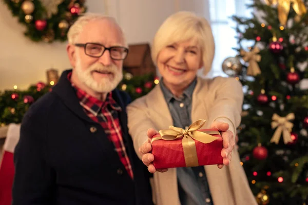 Senior couple holding gift — Stock Photo