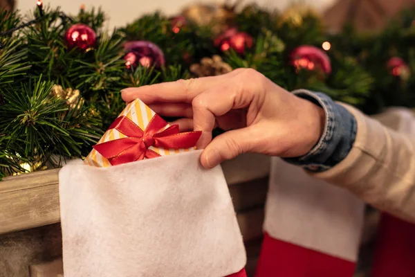 Person putting gift into christmas socks — Stock Photo