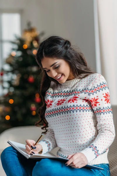 Woman writing in notebook on christmas — Stock Photo