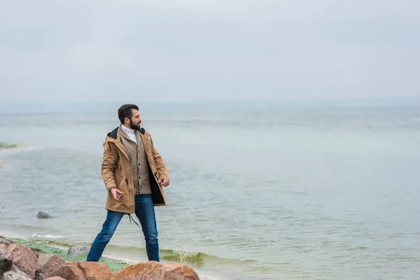 Uomo gettare pietre in mare — Foto stock