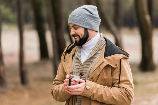 Homem com caneca de bebida quente na floresta — Fotografia de Stock