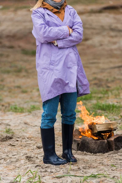 Lonely woman in raincoat near bonfire — Stock Photo