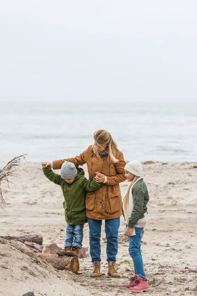 Madre e hijos en la orilla del mar - foto de stock