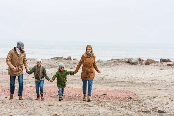 Family holding hands and walking by seashore — Stock Photo