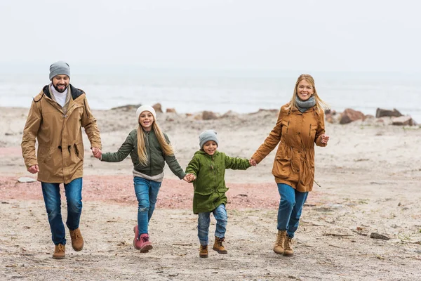 Family holding hands and walking by seashore — Stock Photo