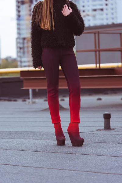 Жінка в коричневому светрі і кольорових штанах — стокове фото