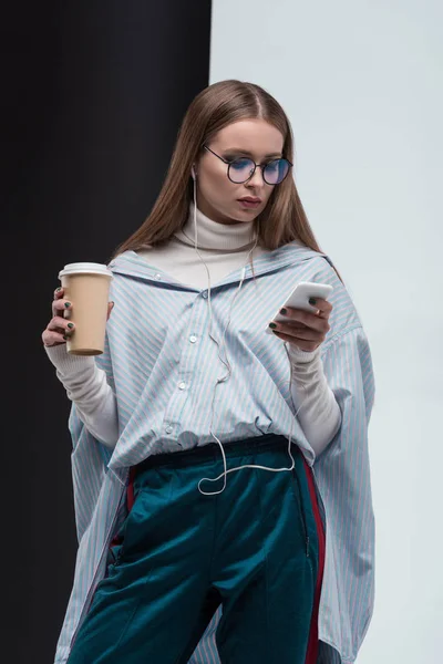 Chica con estilo con teléfono inteligente y café - foto de stock