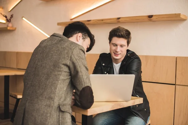 Uomini seduti con computer portatile in caffè — Foto stock