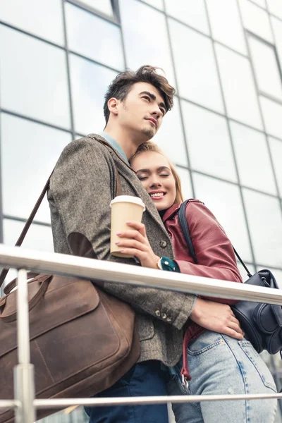 Pareja abrazando y de pie con café - foto de stock