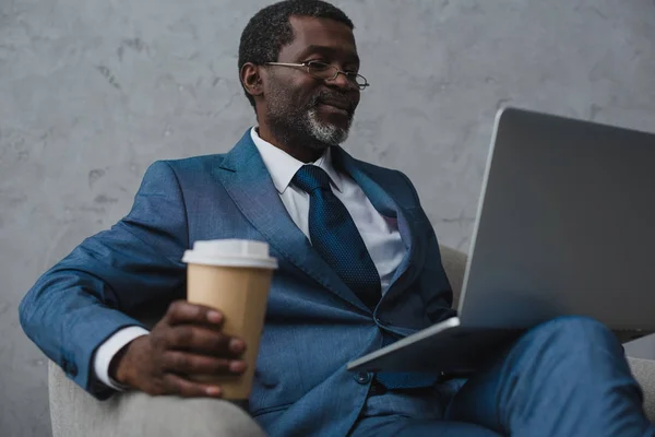 Hombre de negocios sentado con portátil y café - foto de stock