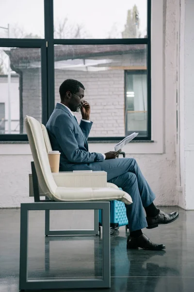 Businessman reading newspaper in airport — Stock Photo