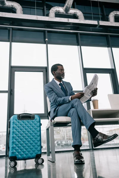 Businessman reading newspaper in airport — Stock Photo