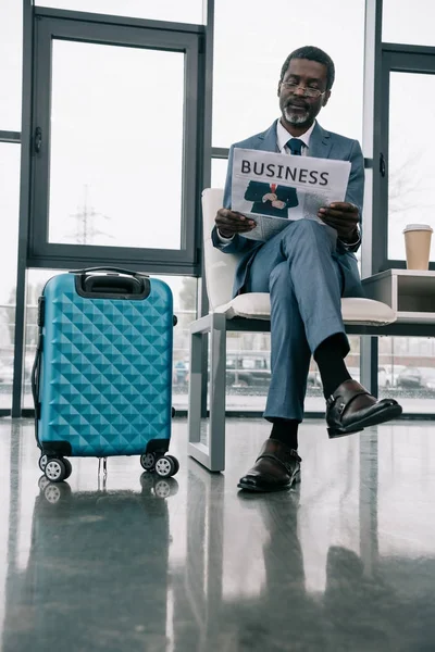 Businessman reading newspaper in airport — Stock Photo