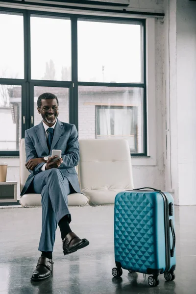 Улыбающийся бизнесмен ждет в аэропорту — стоковое фото