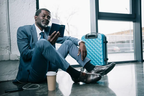 Businessman sitting on floor at airport — Stock Photo