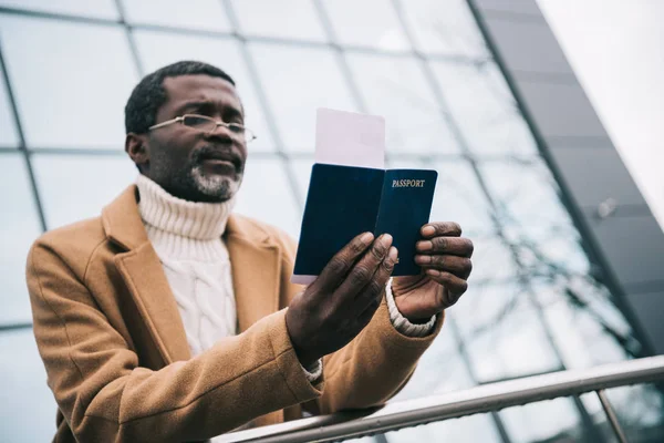 Homem de pé com passaporte e bilhete de avião — Fotografia de Stock