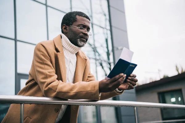 Hombre de pie con pasaporte y billete de avión - foto de stock