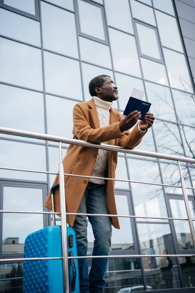 Hombre de pie con pasaporte y billete de avión - foto de stock