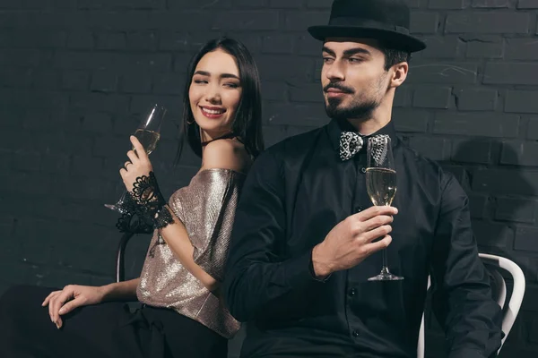 Elegante casal multicultural com copos de champanhe — Fotografia de Stock