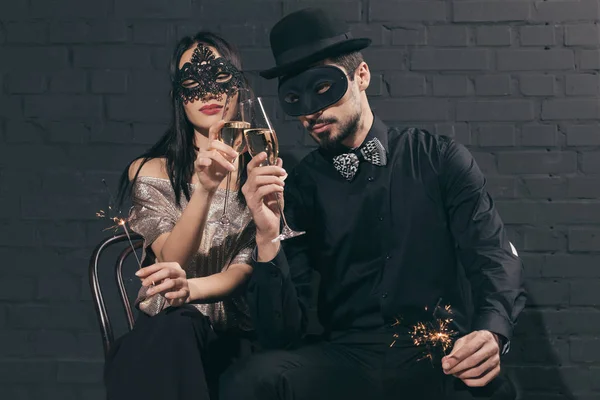 Couple multiculturel dans des masques de Noël avec étincelles — Photo de stock