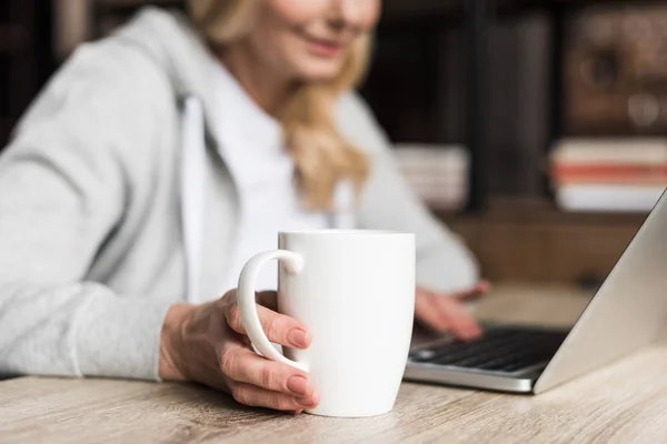 Mujer con café usando laptop - foto de stock