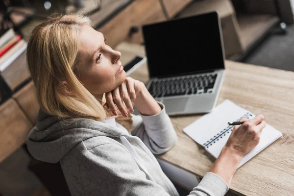 Mujer tomando notas y utilizando el ordenador portátil - foto de stock