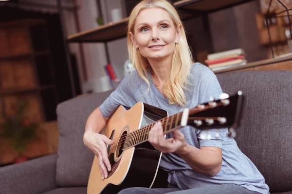 Donna di mezza età con chitarra a casa — Foto stock