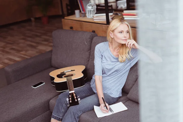 Middle aged woman with guitar at home — Stock Photo