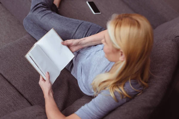 Mujer leyendo libro en casa - foto de stock