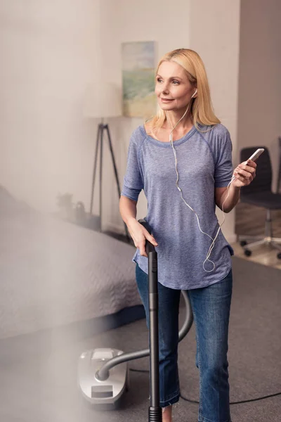 Woman using smartphone and vacuum cleaner — Stock Photo