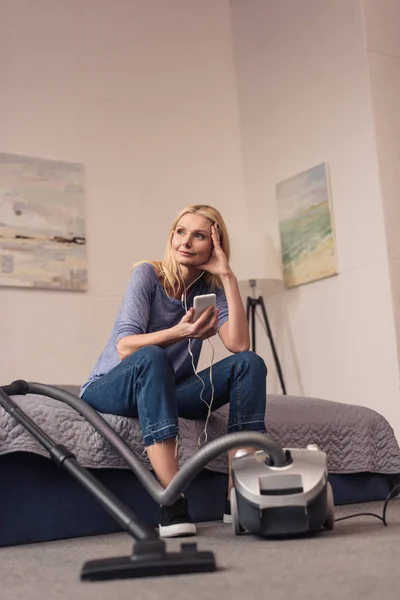 Vacuum cleaner and woman with smartphone — Stock Photo